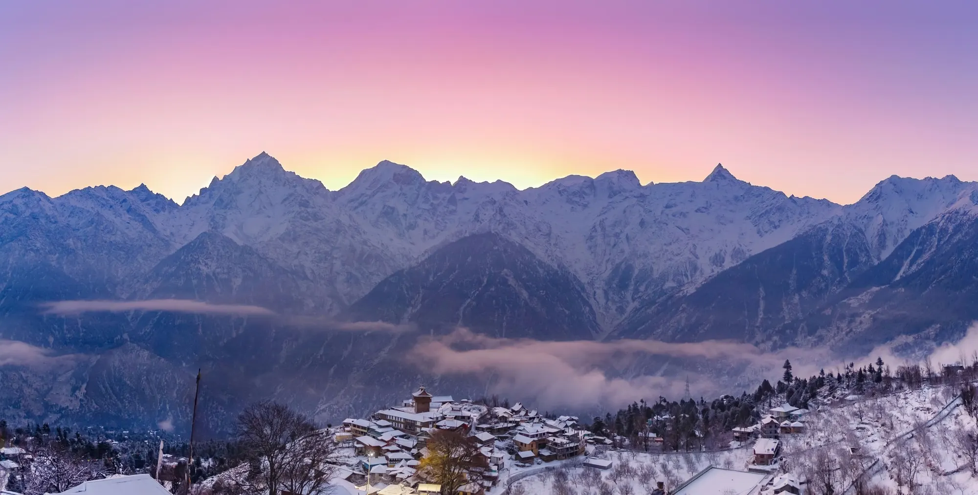 Kinner Kailash range at dawn above the snowy rooftops of Kalpa
