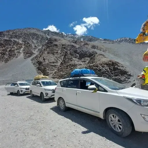 Real white Spiti Darshan vehicles parked on a mountain route
